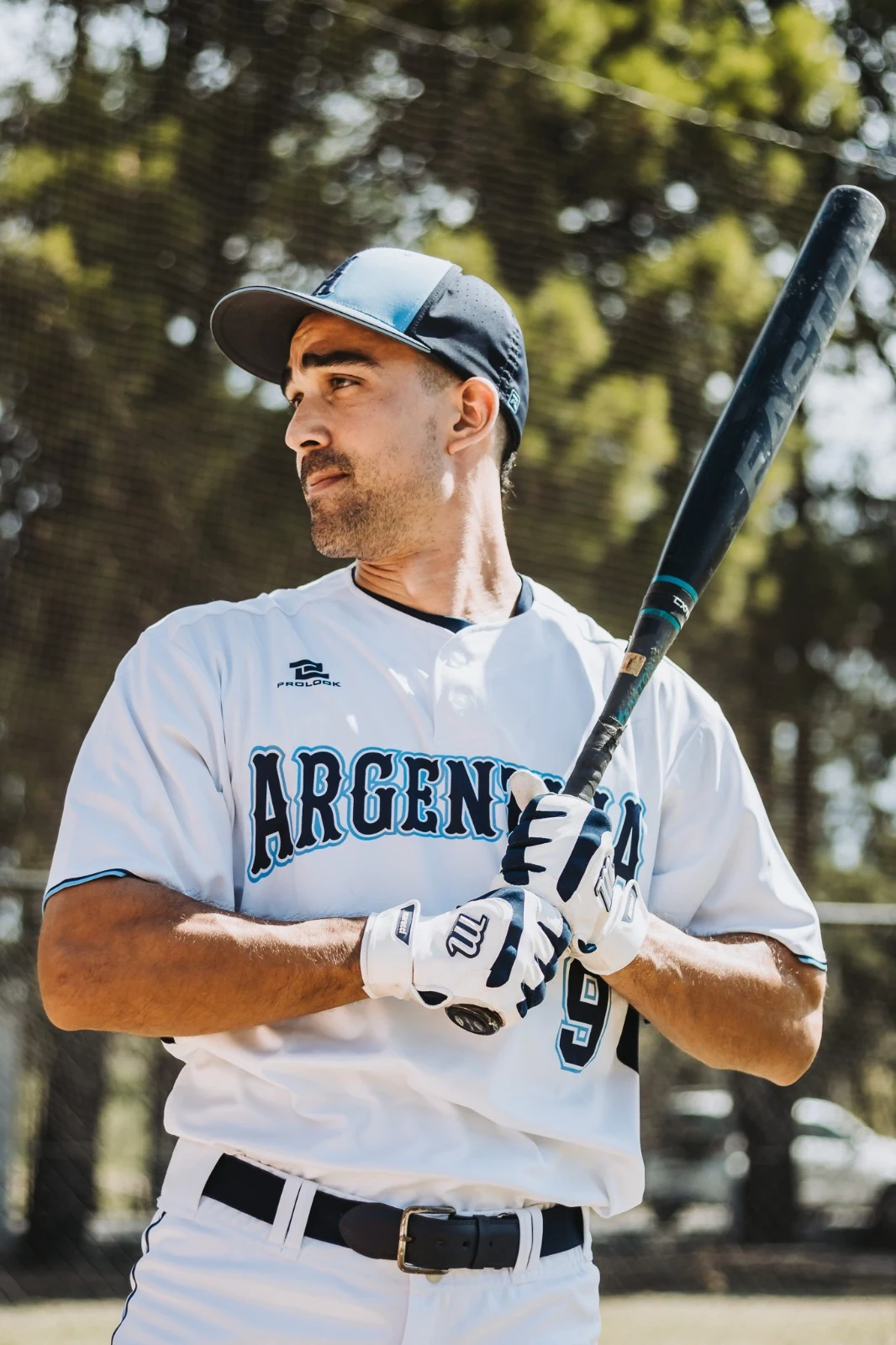 Teo Migliavacca con el uniforme de la Selección Argentina y un bate de sóftbol